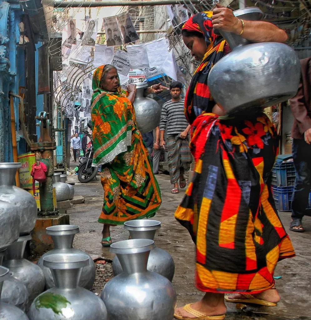 Femmes originaire d'Asie en situation pauvreté en train de porter des jarres d'eau