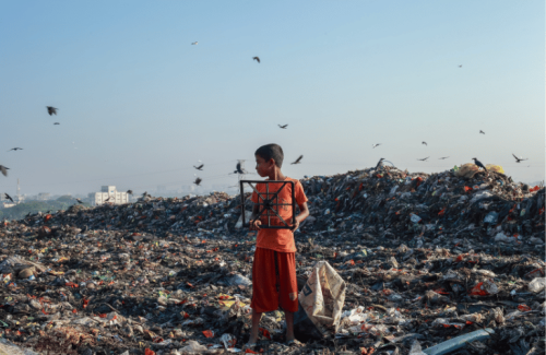 Pollution textile Cette image montre l'inverse de la mode éthique. En effet, un enfant est au milieu d'une très grande décharge de déchets, en majorité textile. Il tient un déchet à la main et des oiseaux naviguent dans le ciel.